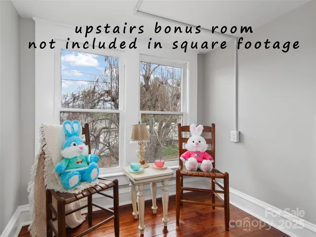 a view of a dining room with furniture one side kitchen view and wooden floor