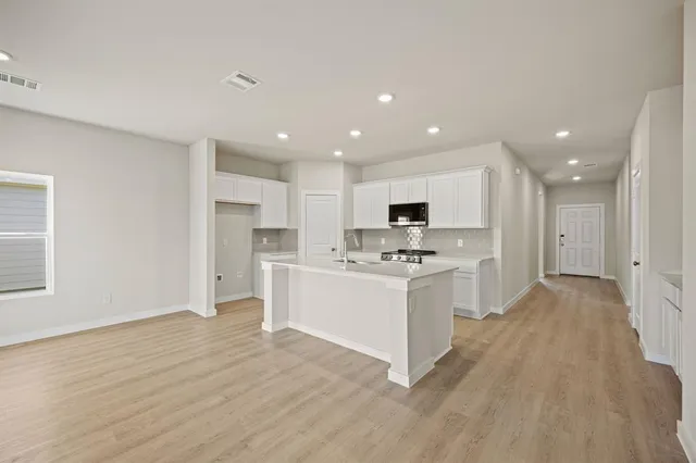 a large kitchen with kitchen island a sink a center island stainless steel appliances and a cabinets
