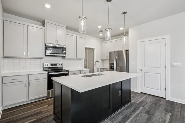 a kitchen with kitchen island a sink stainless steel appliances and white cabinets