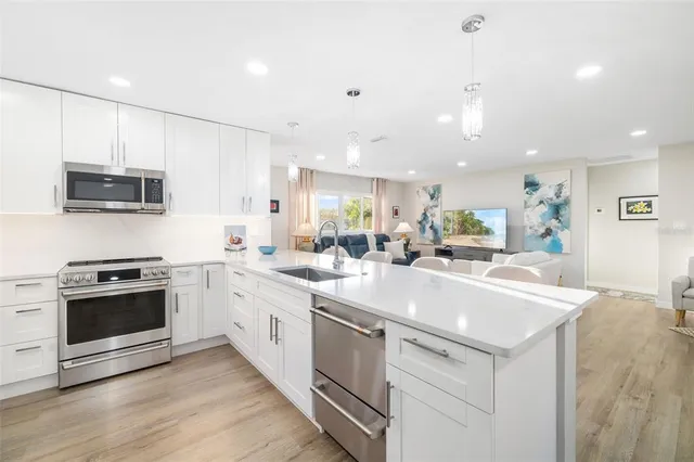 a large white kitchen with a stove top oven a sink and dishwasher with wooden floor