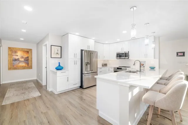 a kitchen with stainless steel appliances a refrigerator a stove a sink a dining table and chairs