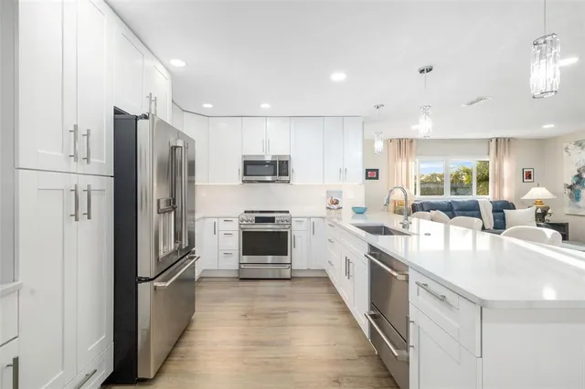 a large kitchen with stainless steel appliances a refrigerator a stove a sink a dining table and chairs