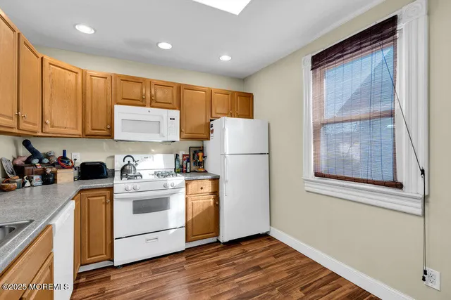 a kitchen with a refrigerator a stove a sink dishwasher and wooden cabinets with wooden floor