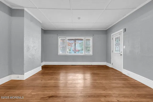 a view of an empty room with wooden floor and a window
