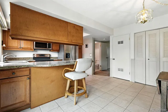 a kitchen with stainless steel appliances granite countertop a stove a sink dishwasher and a refrigerator with wooden cabinets