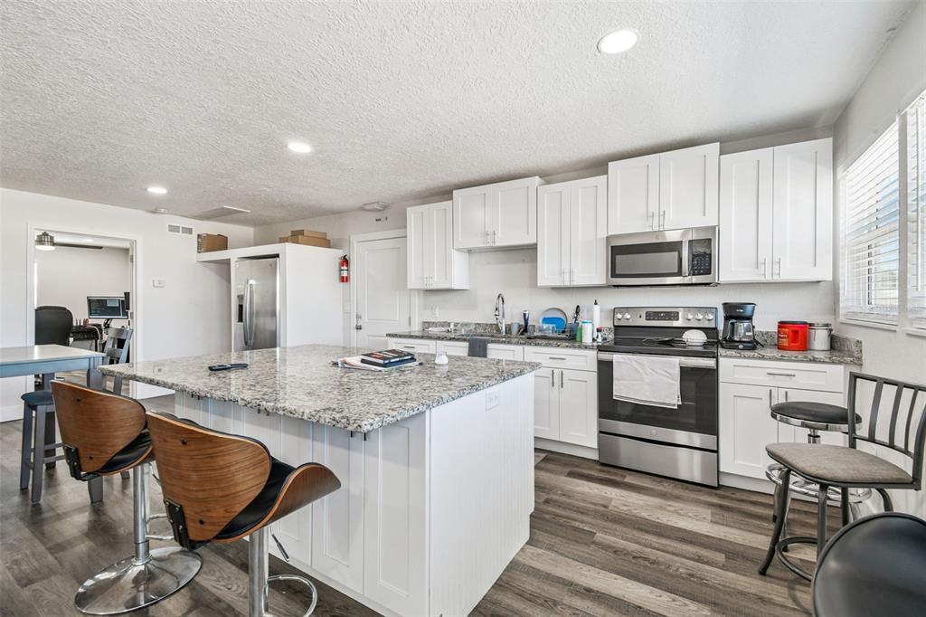 6010 Wall Street Port Richey, FL 34668 - Photo 17 of 43 a kitchen with kitchen island granite countertop a table chairs microwave and cabinets