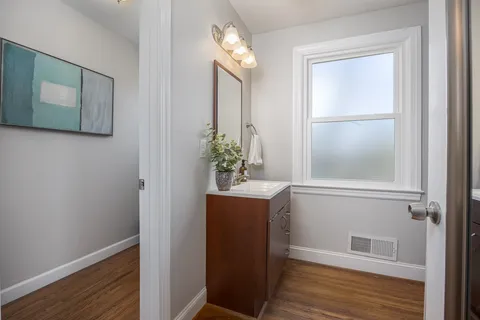 a view of a hallway with wooden floor and cabinet