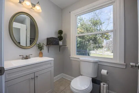 a bathroom with a toilet a sink a mirror and a window