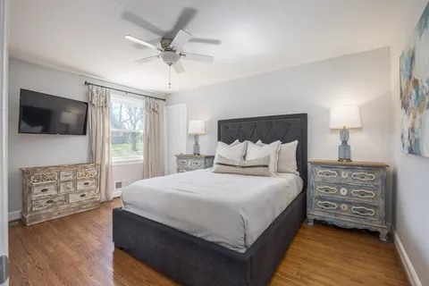 a bedroom with a bed a mirror on the dresser and a flat screen tv