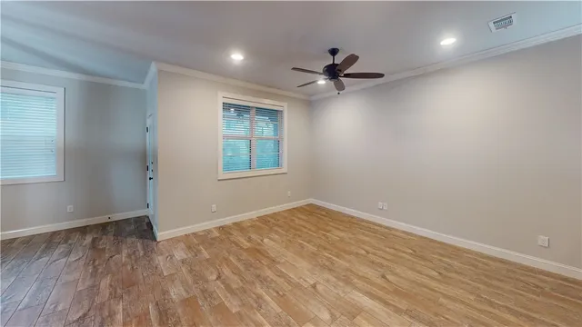 a view of empty room with wooden floor and fan