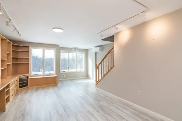 a view of an empty room with a window and wooden floor
