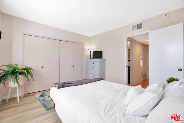 a bedroom with a large bed and a potted plant