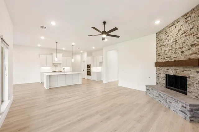 a view of kitchen with kitchen island a fireplace wooden floor and a counter top space