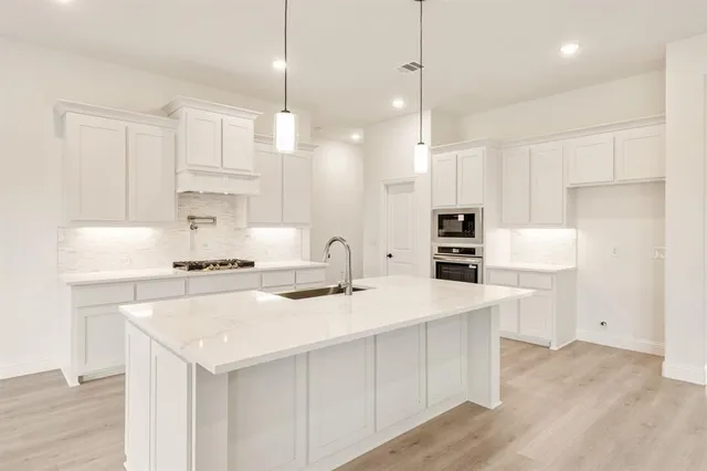 a kitchen with kitchen island a sink a stove a refrigerator and white cabinets