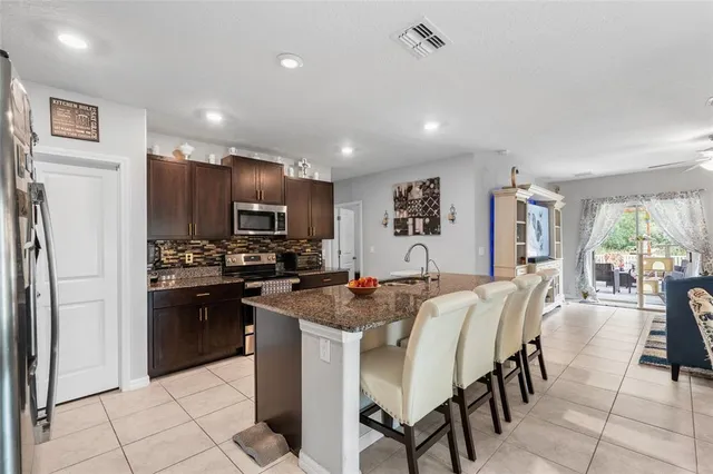 a kitchen with granite countertop kitchen island stainless steel appliances a refrigerator sink stove microwave and cabinets