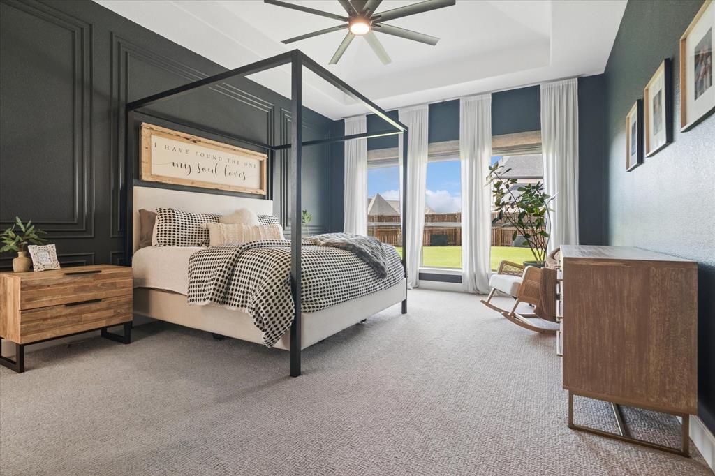 582 Broadleaf Way Haslet, TX 76052 - Photo 16 of 40 Step into your serene primary bedroom with custom accent wall, oversized windows to the backyard, tray ceiling and ceiling fan.