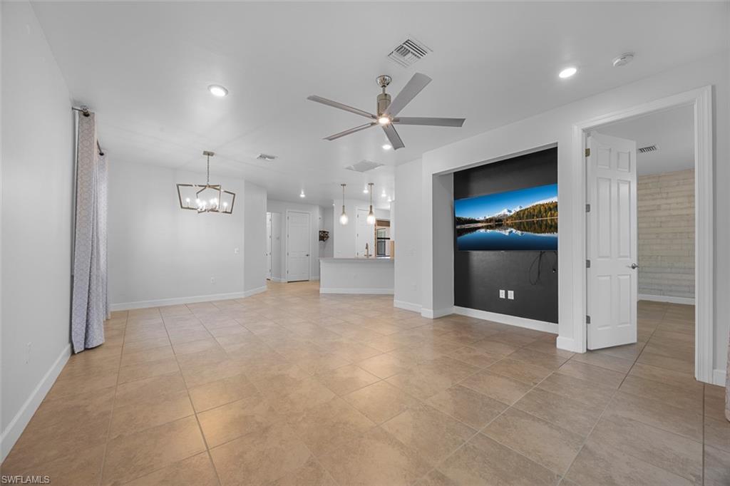 5845 Mayflower Way Ave Maria, FL 34142 - Photo 14 of 48 an empty room with chandelier fan and kitchen view