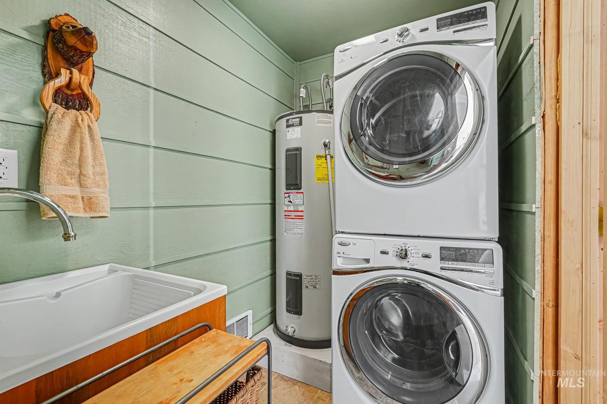106 Wilderness Lake Road Cascade, ID 83611 - Photo 21 of 35 Stackable washer and dryer, laundry sink with a gooseneck faucet, water heater, and horizontal plank wall paneling