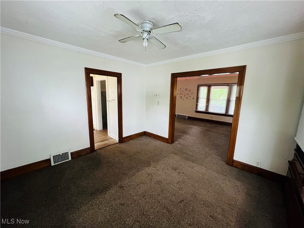 968 Whitby Road Cleveland Heights, OH 44112 - Photo 3 of 19 Spare room featuring ornamental molding, dark carpet, a textured ceiling, and ceiling fan