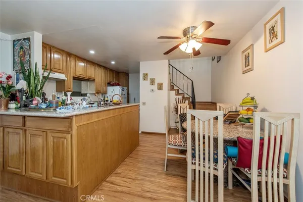 a kitchen with stainless steel appliances kitchen island granite countertop a refrigerator a stove a sink dishwasher and a dining table with wooden floor