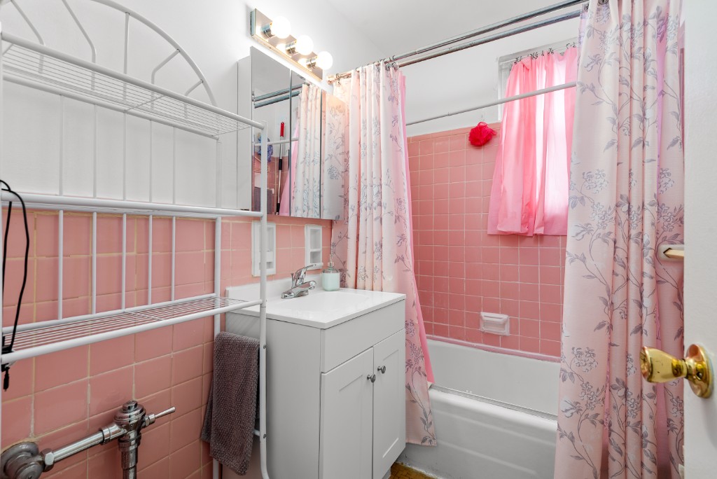 60-11 Broadway, Unit 3C Queens, NY 11377 - Photo 17 of 18 a bathroom with a sink a bath tub and a shower curtain