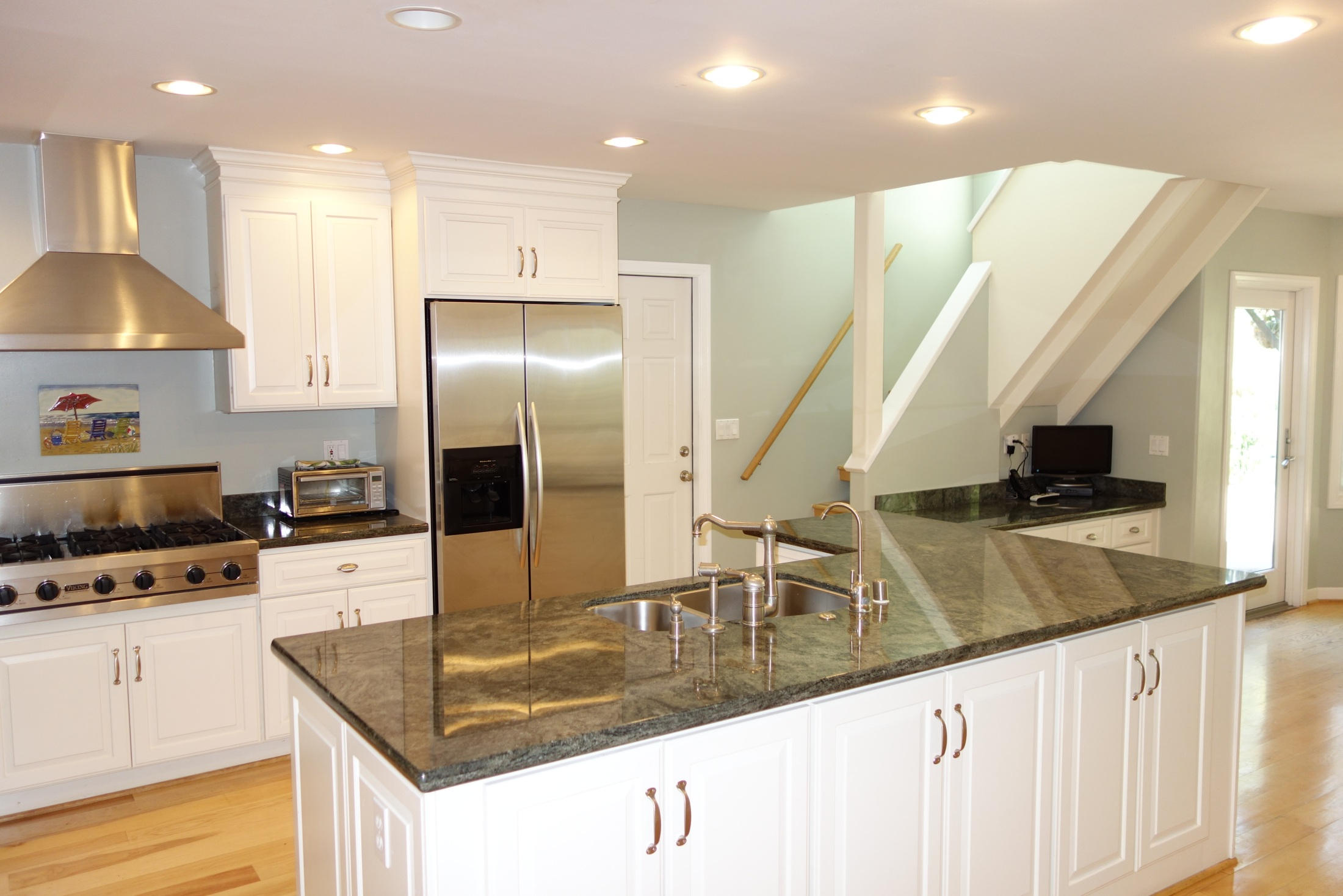 a kitchen with stainless steel appliances granite countertop a sink a stove and a refrigerator