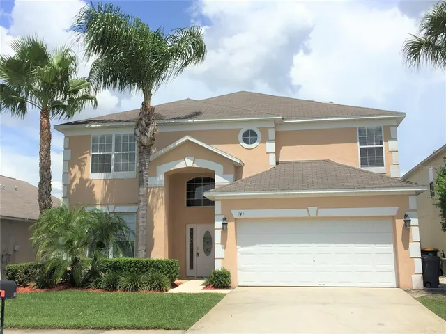 front view of house with a yard and palm trees