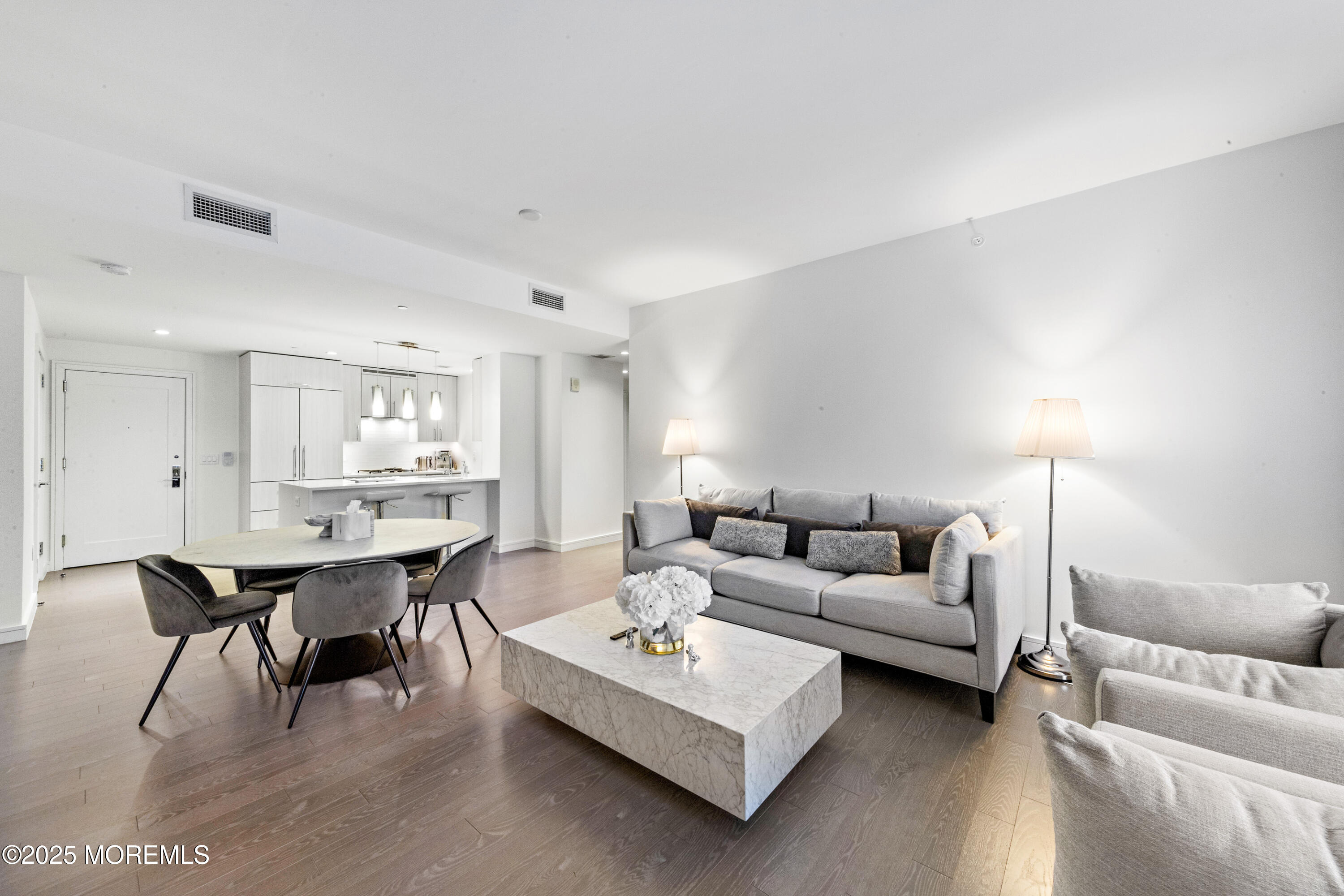 a living room with furniture a table and kitchen view