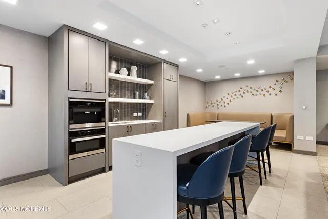 a kitchen with stainless steel appliances kitchen island granite countertop a table chairs and a refrigerator