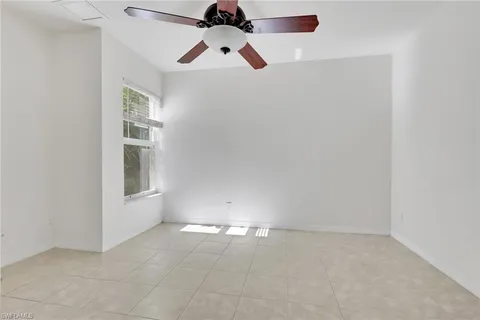 an empty room with ceiling fan and window