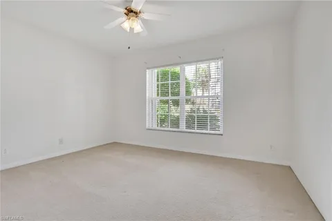 an empty room with a window and a fan