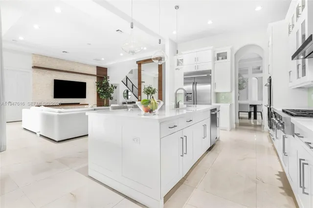 a large white kitchen with stainless steel appliances kitchen island granite countertop a sink and white cabinets