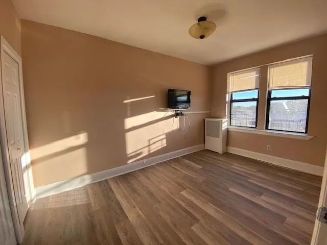 a view of an empty room with a window and wooden floor
