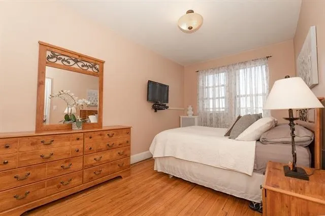 a bedroom with a large bed and a flat tv screen on dresser