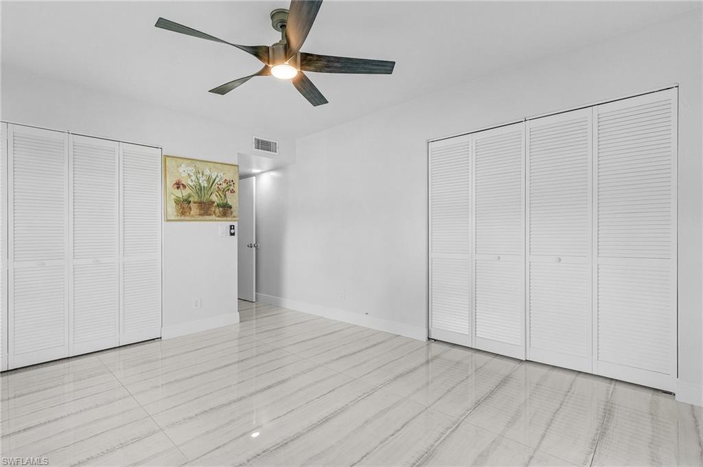 1765 Courtyard Way, Unit C202 Naples, FL 34112 - Photo 15 of 25 Unfurnished bedroom with multiple closets and a ceiling fan