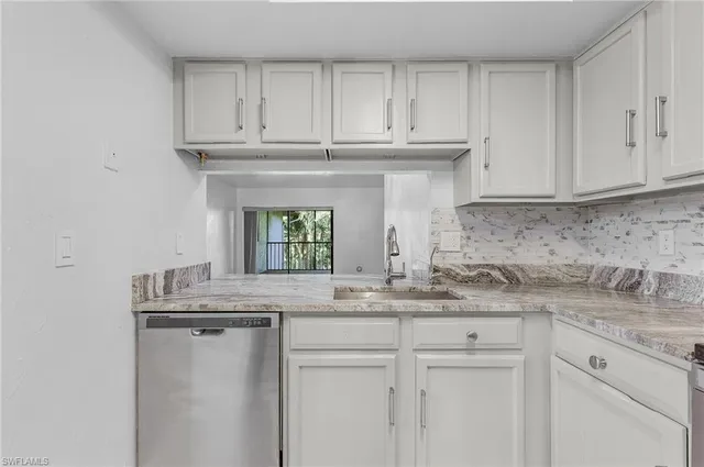 a kitchen with granite countertop white cabinets and a sink