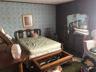 a bed sitting in a bedroom next to a window with wooden floor