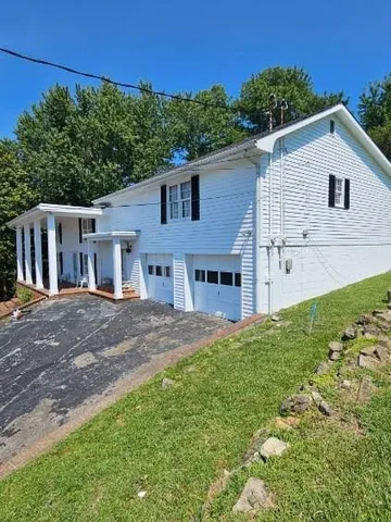 a view of a yard in front of a house with large tree