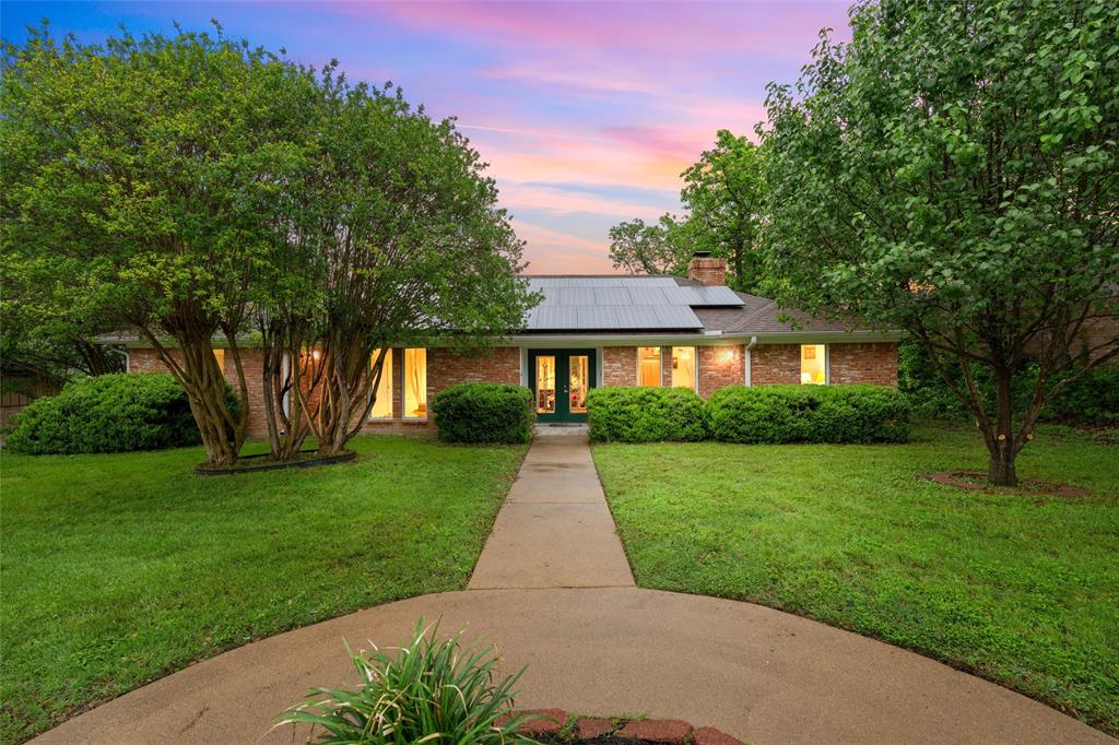 Brick facade residence featuring solar panels, a central entryway, and a concrete pathway
