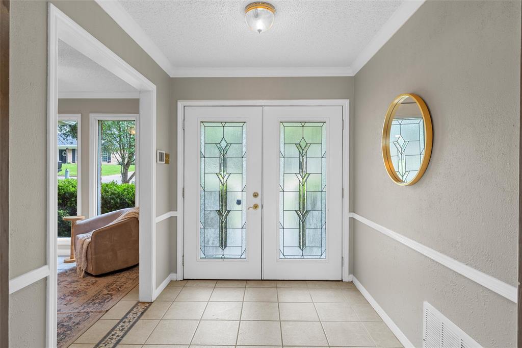 3301 Loma Vista Drive Waco, TX 76708 - Photo 2 of 29 Entryway featuring double doors with decorative glass panels, neutral wall tones, white crown molding, and tiled flooring with an accent border