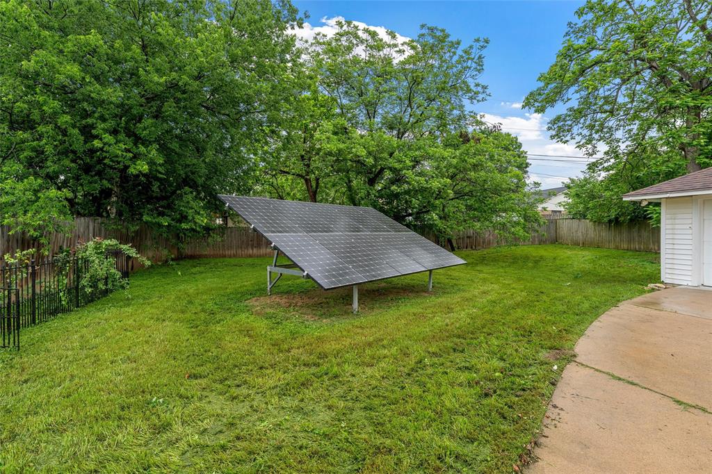3301 Loma Vista Drive Waco, TX 76708 - Photo 25 of 29 Expansive backyard featuring a ground-mounted solar panel array, a concrete patio, and mature trees providing natural screening