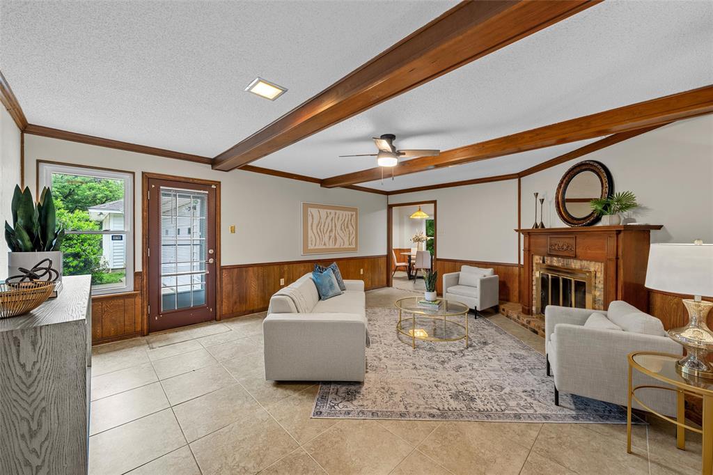 3301 Loma Vista Drive Waco, TX 76708 - Photo 7 of 29 Living area featuring exposed wood beams, tile flooring, wood paneling, a fireplace with a wood mantle, and a ceiling fan