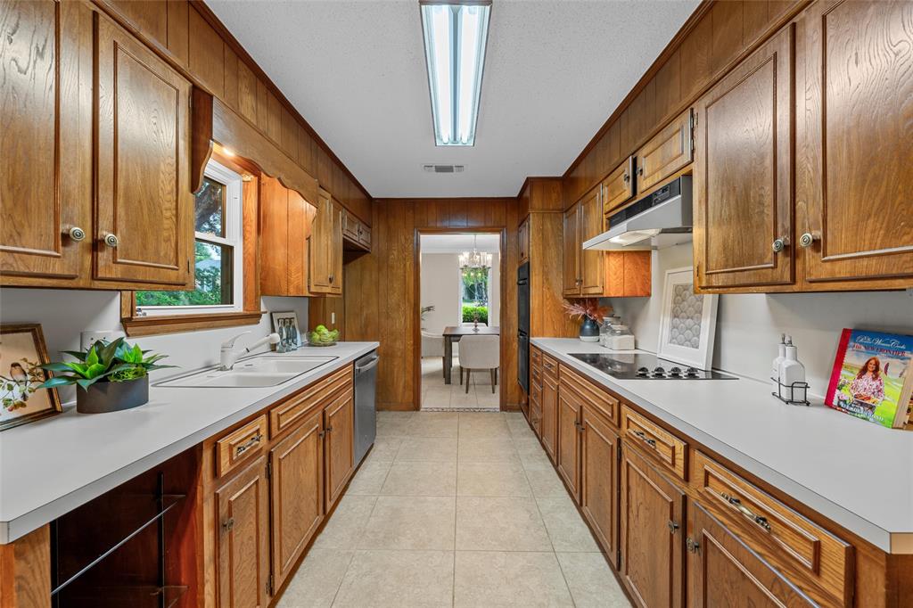 3301 Loma Vista Drive Waco, TX 76708 - Photo 8 of 29 Galley kitchen featuring extensive wood-finish cabinetry, solid surface countertops, a built-in electric cooktop, double wall ovens, and a recessed ceiling light fixture
