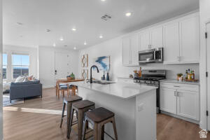907 West Bright Ridge Ln Street, Unit 1430 St. George, UT 84790 - Photo 6 of 19 Open-concept living space with wood-finish flooring, white cabinetry, stainless steel appliances, a kitchen island, and recessed lighting