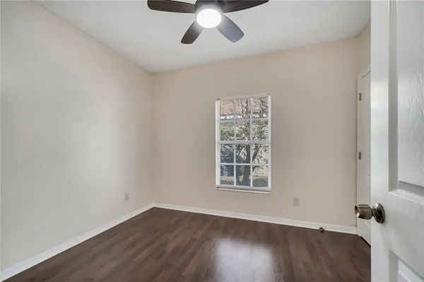 an empty room with wooden floor chandelier fan and windows