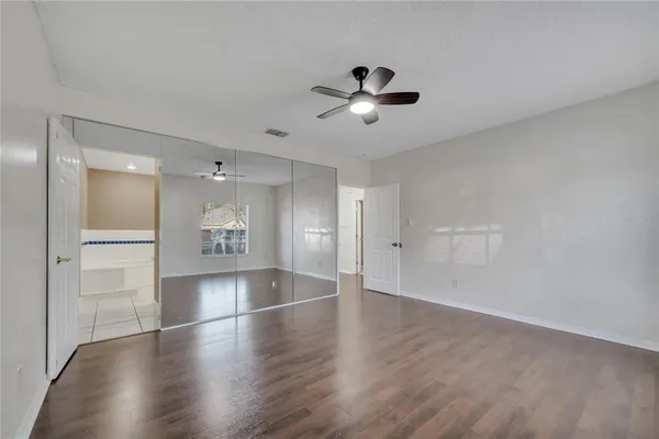 a view of empty room with wooden floor and fan