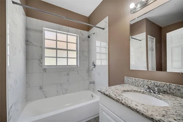 a bathroom with a granite countertop sink mirror and a bathtub