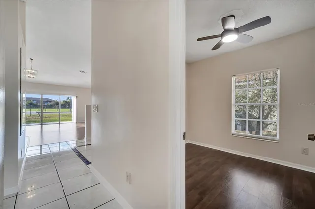 an empty room with wooden floor fan and windows