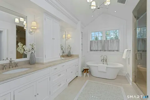 a spacious bathroom with a double vanity sink mirror and bathtub