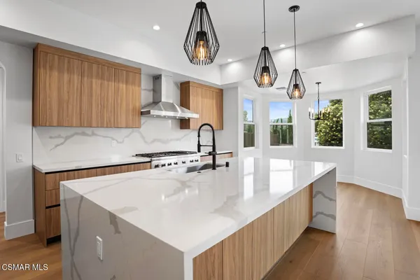 a large kitchen with stainless steel appliances a large counter top a sink a window and wooden floor